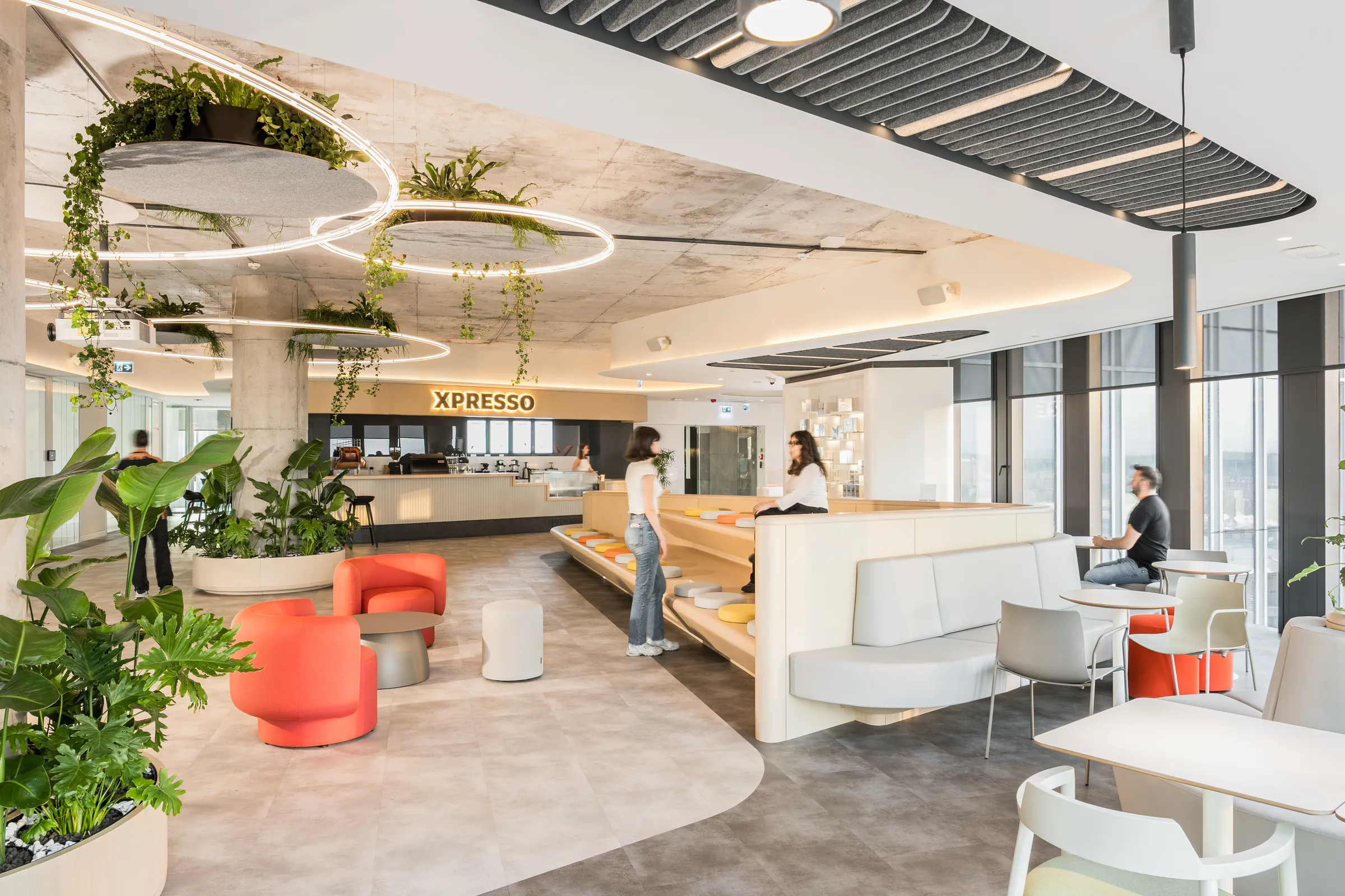 The HubX office lounge with hanging plants, the XPRESSO café and people at work