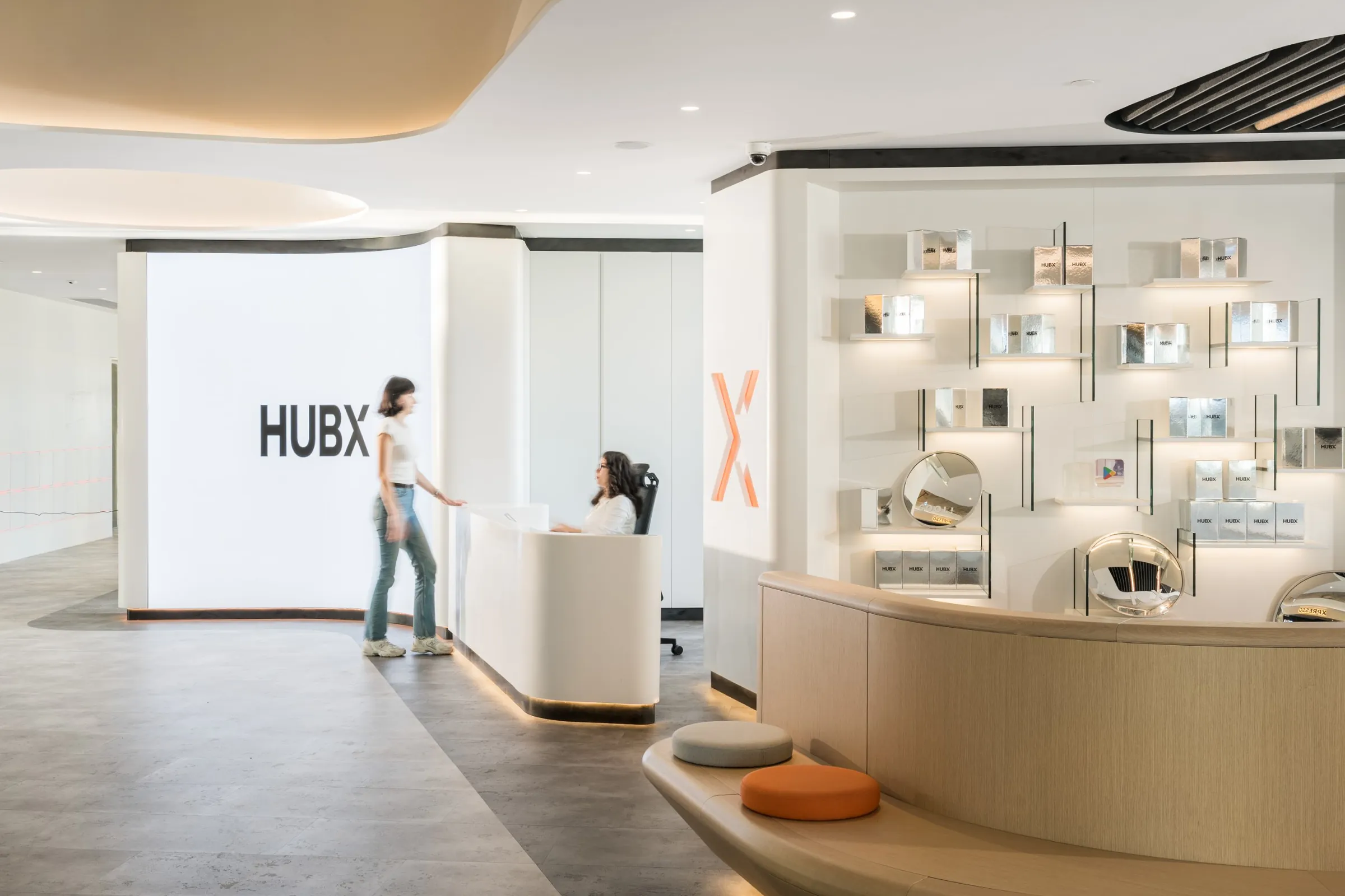 The HubX office reception: a lit HUBX wall, the front desk and a shelf of silver HubX boxes